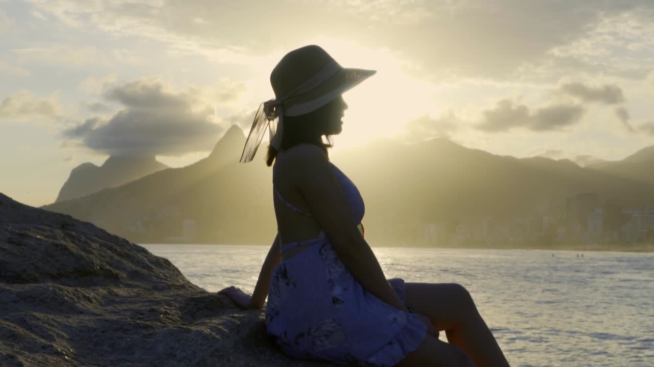 hermosa mujer asiática viendo una puesta de sol en la playa de ipanema en río de janeiro