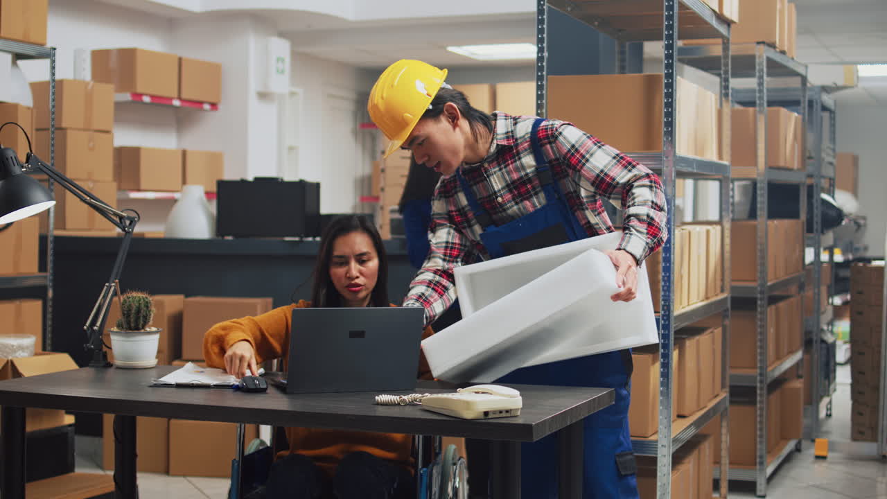 Workers in a warehouse moving boxes and working with a laptop