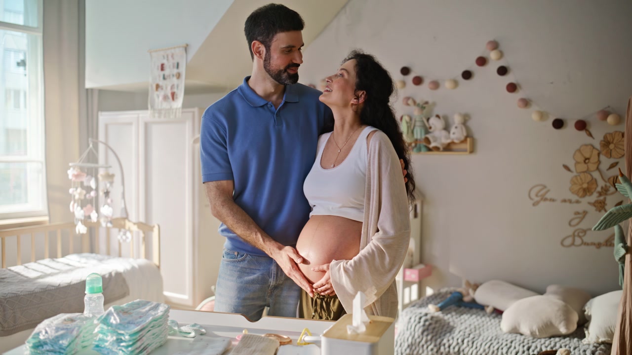Futuros padres tocando el vientre en la habitación del bebé. Esposa embarazada y marido creando un vínculo en casa