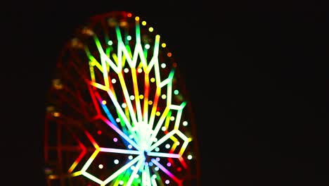 video desenfocado borroso de un paseo en la rueda de ferris brillantemente iluminado girando por la noche