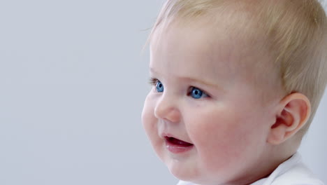 close up of happy baby boy sitting on parents bed