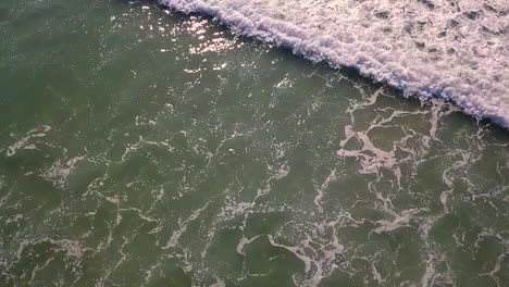 imágenes aéreas de olas rodando hacia la costa en aguas turquesas frente a la costa del sur de california