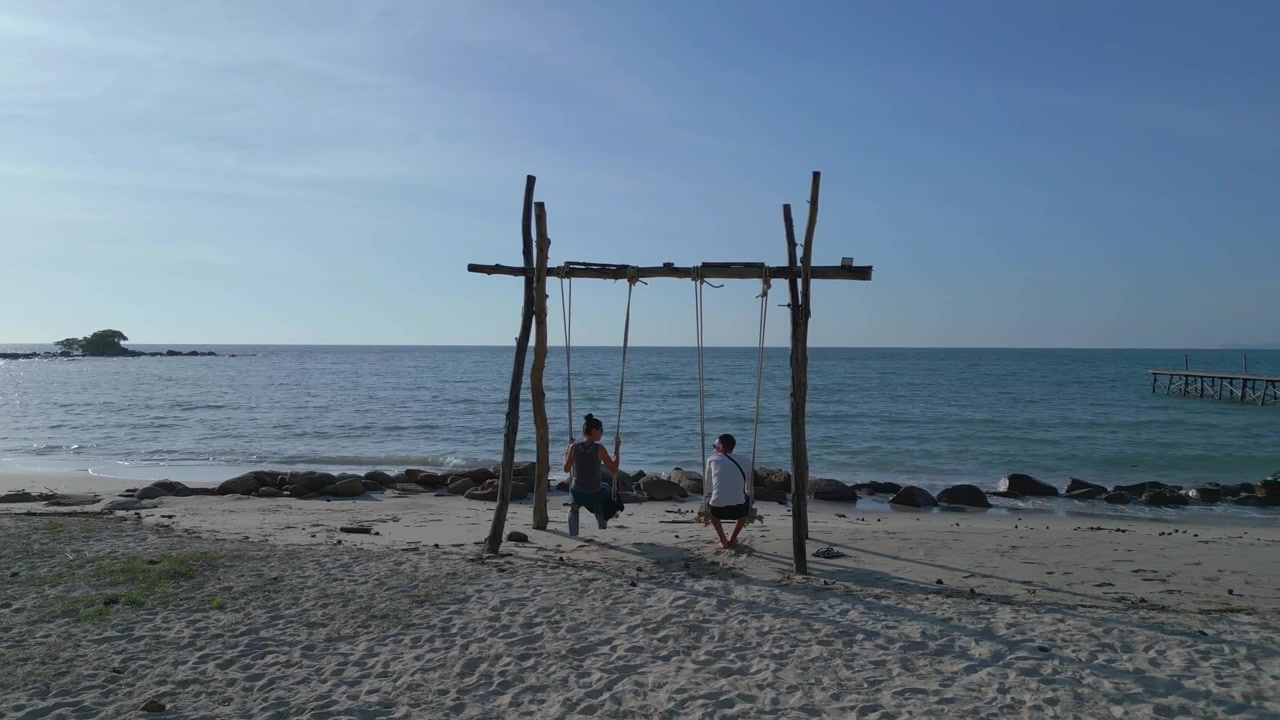 Coppia di Innamorati Felici in Luna di Miele. Incredibile Vista Aerea di un'Altalena su una Paradisiaca Spiaggia di Sabbia Bianca, sull'Isola da Sogno Ko Kut, Thailandia 2022. Filmato Cinematografico con Drone 4K UHD con Carrellata a Destra