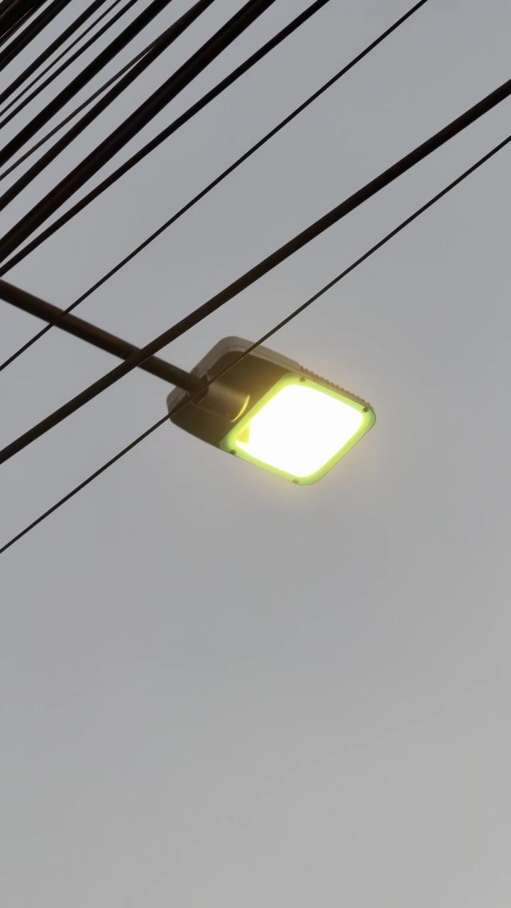 Lampadaire LED lumineux sur fond de ciel de soirée gris.