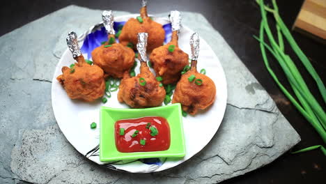 el chef sirvió la piruleta de pollo crujiente bien cocinada y la salsa de tomate con cebolla verde cortada en un plato