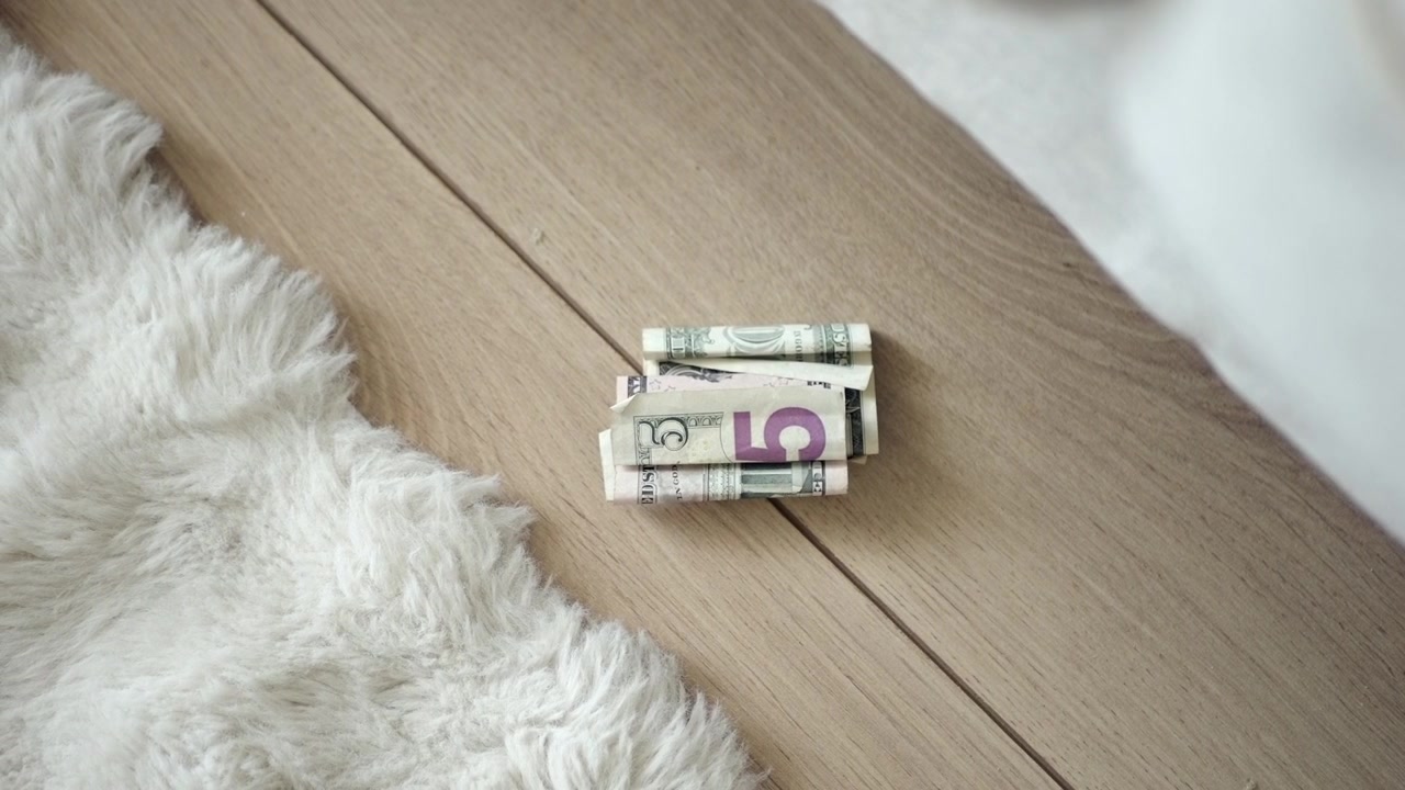 Stack of Rolled US Five Dollar Bills on Wooden Floor