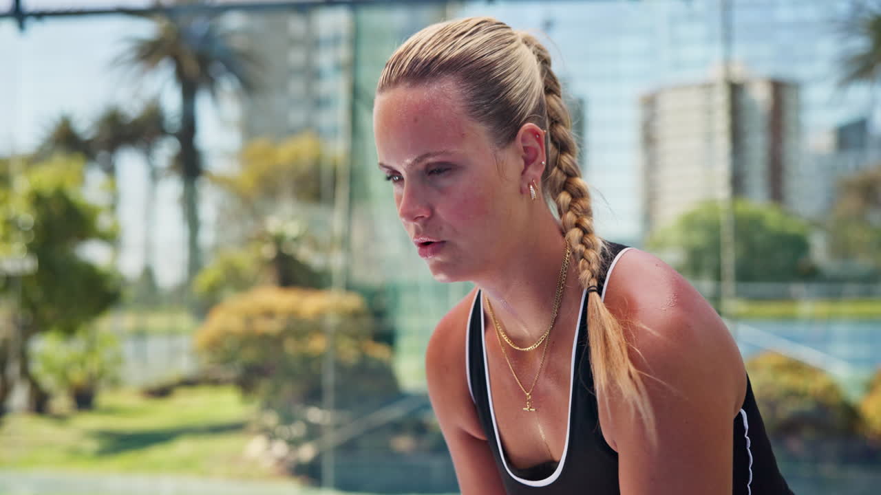 Giovane donna concentrata che riprende fiato durante una partita di padel