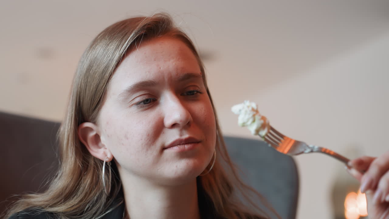 Kaukasisk kvinde smager salat med gaffel, nærbillede portræt i hyggelig bistro, madblogger nyder friske grøntsager og cremet dressing, mildt smil og eftertænksomt udtryk, blød omgivende belysning.