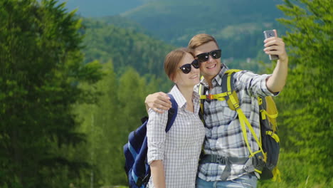 una pareja joven de turistas con mochilas se toman fotos con un teléfono inteligente en una hermosa