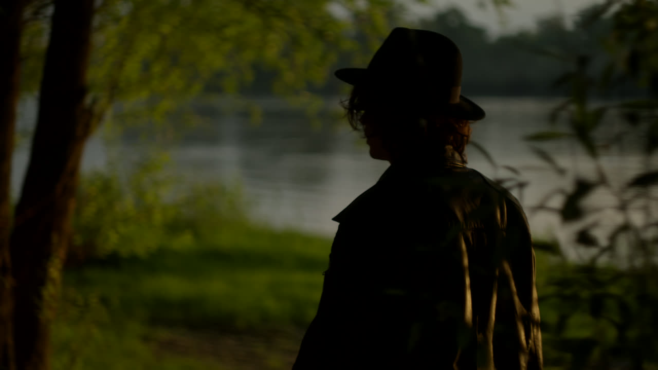 Silhouette of a person by a river at sunset