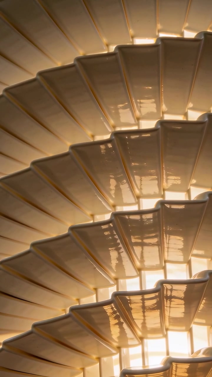 Vertical video: Panning camera revealing pendant lamp spiral to reveal lower tiers and warm light
