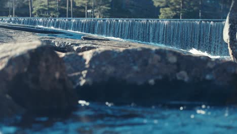 cascada de agua desde la rampa de hormigón en el río poco profundo