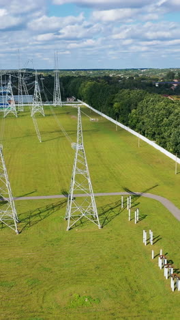 panoramic view on a field with electric towers. high- voltage power lines with wires on the background of green nature in rural place. vertical video