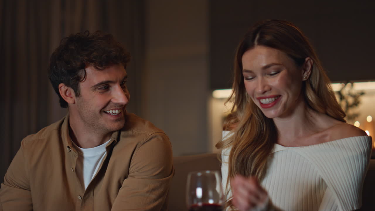 Cute soulmates enjoy date with wine at evening apartment close up. Happy couple