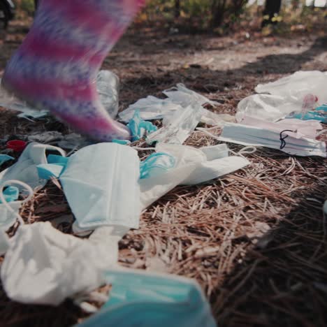 The-child's-feet-in-boots-walks-through-the-woods-past-a-pile-of-garbage-1