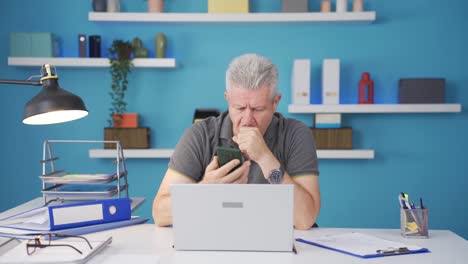 Home-office-worker-man-gets-frustrated-while-looking-at-phone.