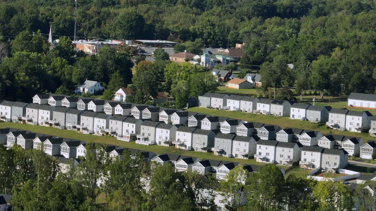 Aerial view of peaceful American neighborhood with rows of houses surrounded by lush greenery, showing suburban community of town. Wide shot. Colonial style townhouses with two-story