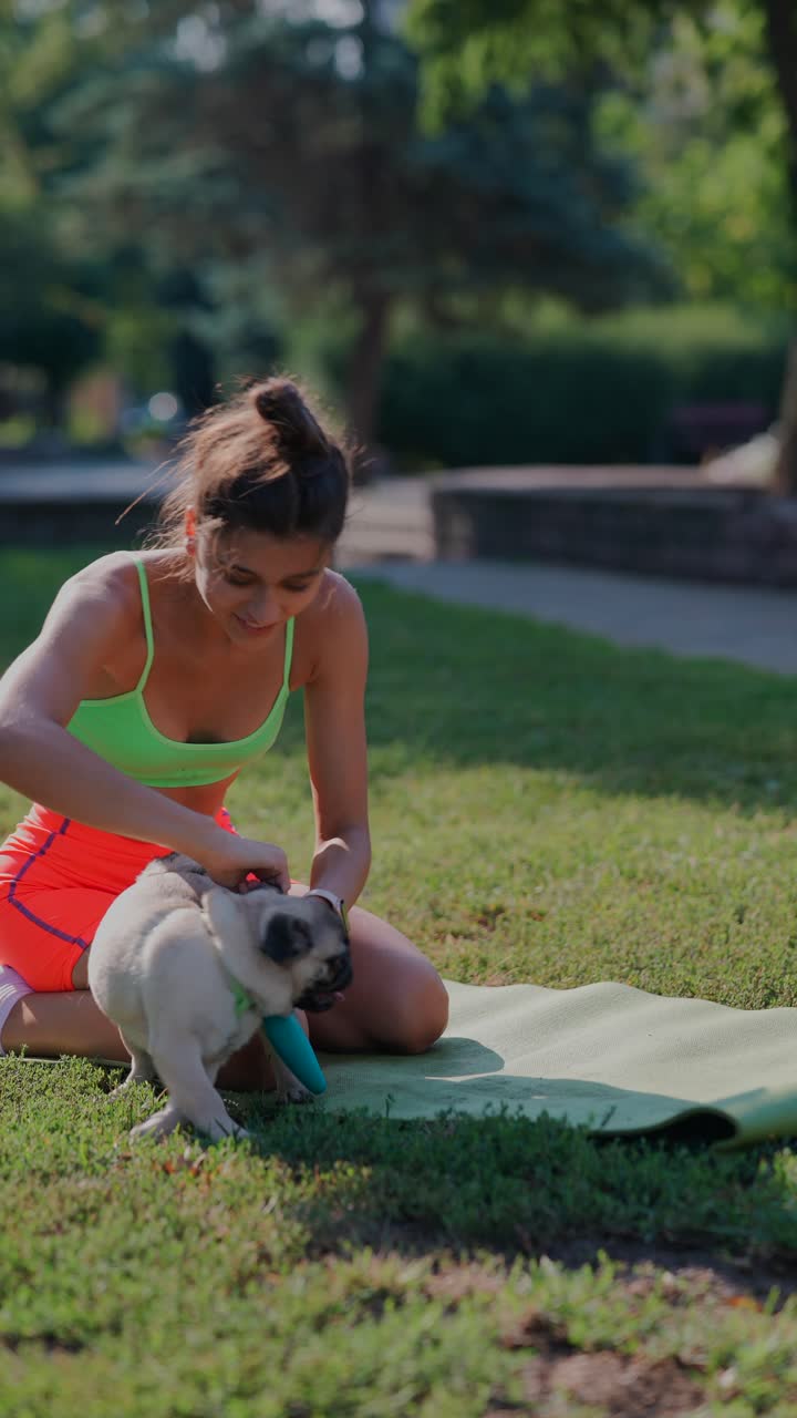 mujer jugando con su pug en un parque