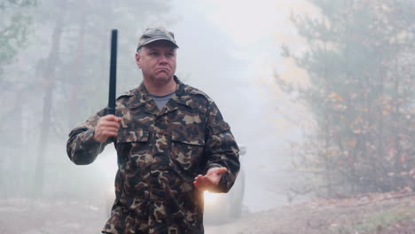 portrait of an angry security guard in camouflage uniform with a rubber baton in his hands