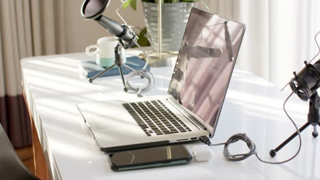 a laptop sits on a white desk beside a coffee cup and a potted plant at home