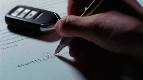 -Close-up-low-angle-shot-of-a-female-caucasian-hand-signing-a-document,-car-key-fob-in-background