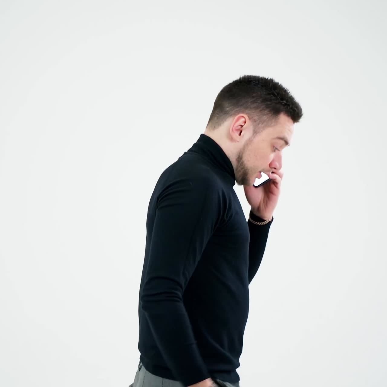 Handsome man having phone talk indoors. Serious young businessman talking on a cellphone and moves slowly isolated on white background. Slow motion.