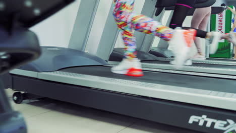 close-up of women's legs in sport trainers running on the treadmills in a new gym. fitness and healthy lifestyle concept.