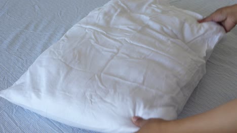 woman arranging a white pillow on a bed
