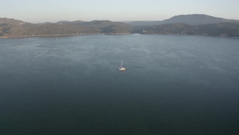 Drone-aerial-footage-of-one-catamarans-in-the-ocean-on-golden-hour-with-an-overcast-weather-on-background-4K