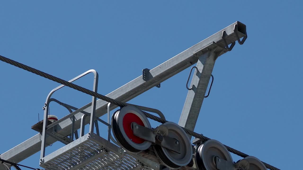 Static low angle shot of metal pulley wheels spinning on a ski lift cable system