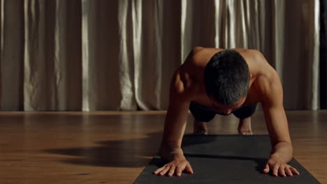 Hombre-En-Forma-Y-Atlético-Haciendo-Una-Tabla-En-Una-Habitación-Oscura-A-Altas-Horas-De-La-Noche