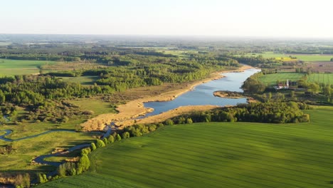 scenic drone footage of a river, green farm fields and trees in central europe