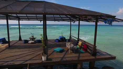 Terraza-De-Playa-Pública-De-Vacaciones-De-Ensueño,-Plataforma-De-Muelle-De-Madera-Con-Asientos-Balineses,-Increíbles-Vistas-Al-Mar,-Toma-De-Un-Dron-En-Movimiento,-Gili-Trawangan,-Bali,-Indonesia