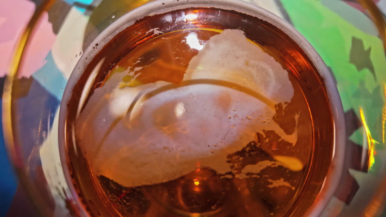 Bicchiere di birra ambrata con un po' di schiuma, primo piano e in avvicinamento.