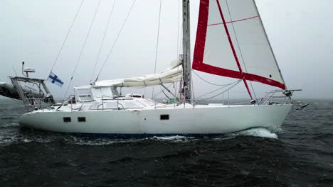 white sailboat, sailing during a snowstorm on the open sea - aerial view