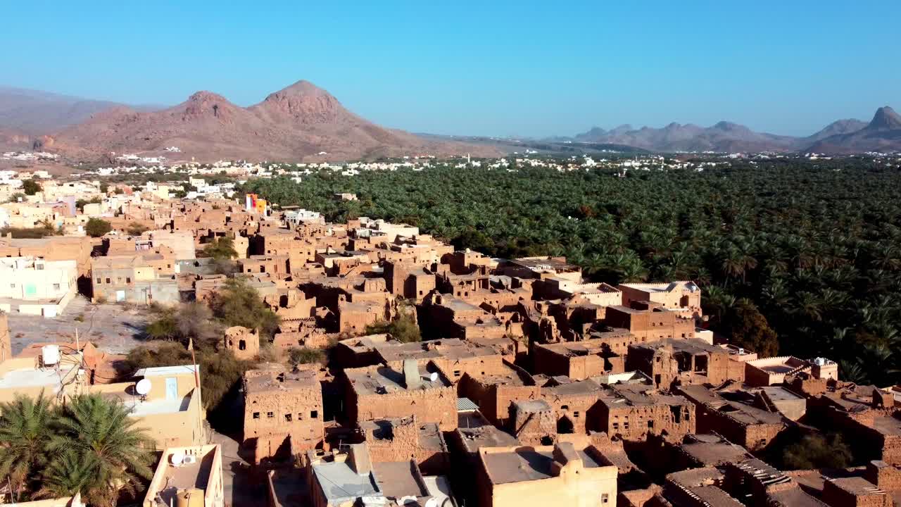 Aerial view of Al Hamra Old Town, Oman! Discover centuries-old mud houses and Hajar Mountain views. Watch now!