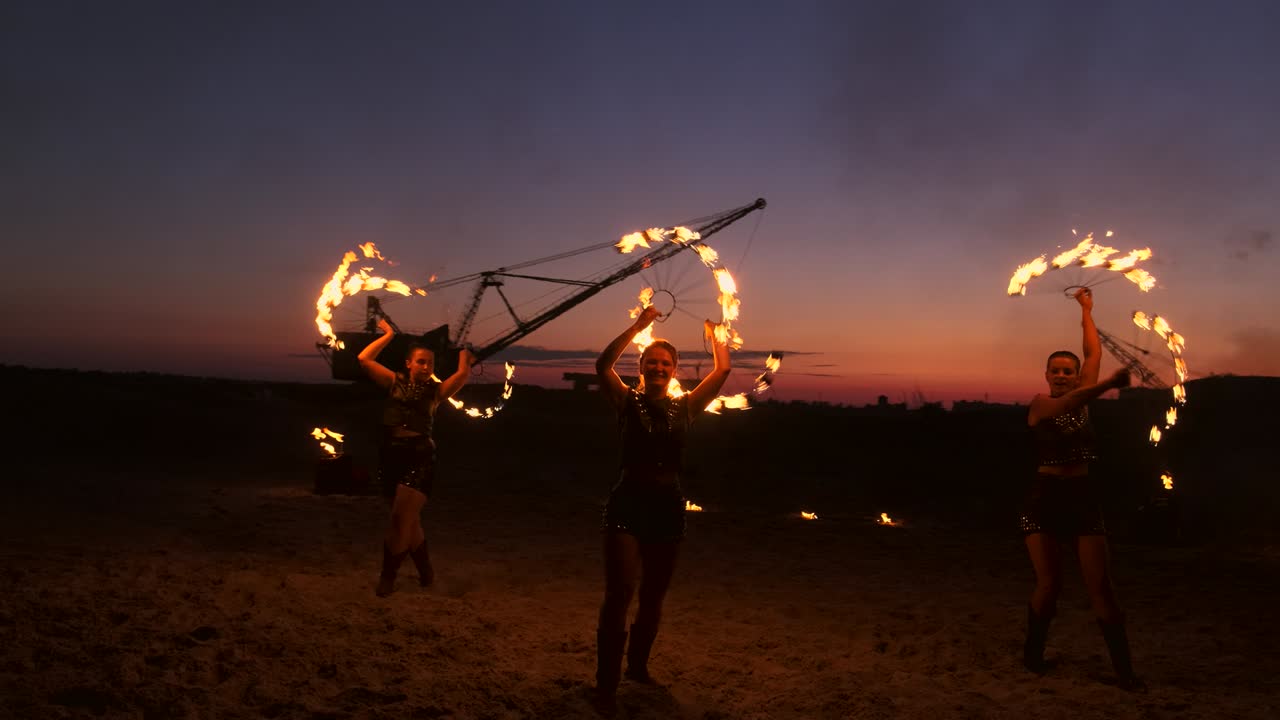 группа профессиональных артистов исполняет различные пожарные сооружения. мальчики и девочки исполняли танцы с огнем ночью на улице в парке.