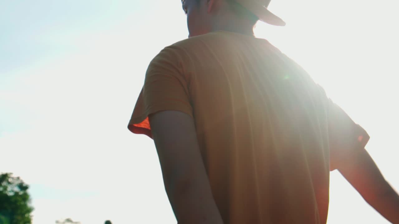 Young man bend over to pick up rock near river to skip rocks, low angle shot