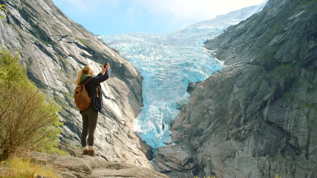 mujer tomando una foto de un glaciar en noruega