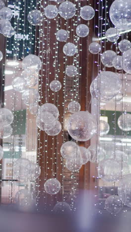 primer plano de decoración festiva brillante con esferas translúcidas suspendidas en cuerdas, creando un ambiente mágico con reflejos de luz suave, ideal para decoración de vacaciones o eventos de centros comerciales