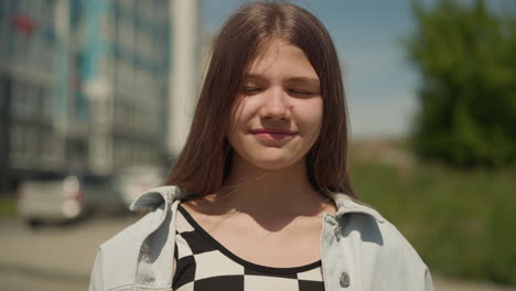 Girl-stands-near-high-rise-building-closing-eyes-dreamily