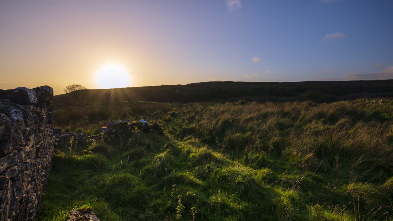 아일랜드의 슬라이고 카운티의 카로킬에서 볼 수 있는 극적인 구름이 가득한 일몰 저녁 동안 오래된 돌벽 폐허와 함께 시골 자연 농경지의 타임 스