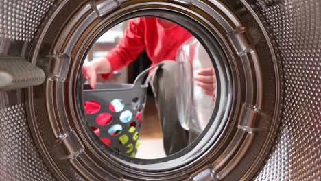 view from inside the washing machine drum. young man is loading laundry in washing machine. view from inside