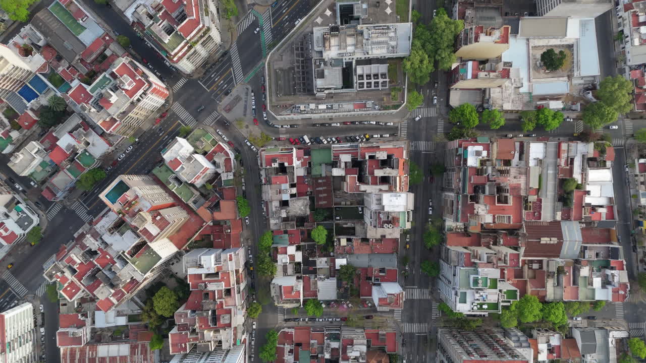Aerial overhead drone shot of a busy city with residential buildings, streets, and green spaces, showing the vibrant city life in Buenos Aires