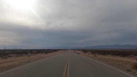 from the point of view of a person driving a car through the mojave desert on a stormy day