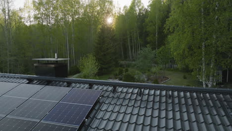 aerial: sun flares in middle of forest, revealing solar cells on a house roof