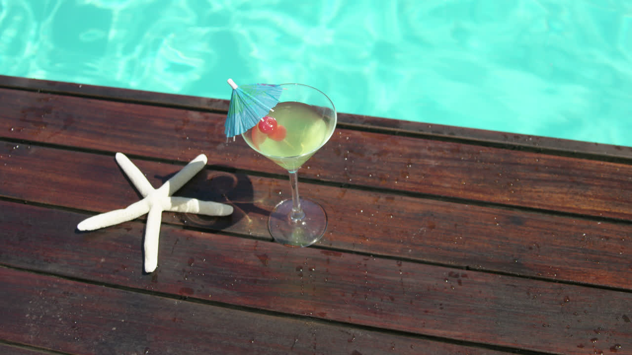 Cocktail glass and fake starfish near swimming pool