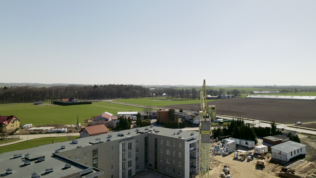sitio de construcción del edificio del panel seccional con grúa trabajando en el lugar en lubawa polonia durante el día - dron lento movimiento descendente sobre el edificio