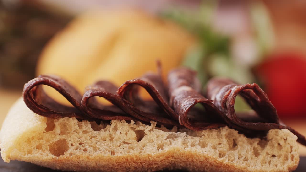black bull sausage ham, tongue pork dry-cured sausage on a black background, traditional spanish delicatessen food, close up.
