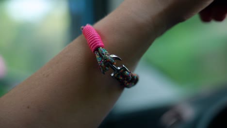 a colorful bracelet on a female driver’s wrist while driving a car